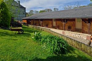 a brick building with a wheelbarrow in front of it at Auberge Les Tonnelles in Saint-Léonard