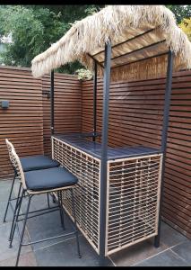 a table and a chair under a straw umbrella at Cozy and warm family home in South Norwood