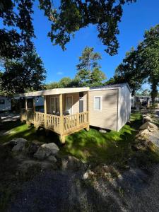 a mobile home with a deck on the grass at Mobil home sur le bassin d'Arcachon in Lège-Cap-Ferret