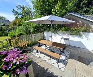 a wooden table and a bench with an umbrella at Beautiful 2 bedroom annexe in popular town location in Pembrokeshire