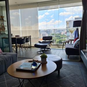 een woonkamer met een tafel en een groot raam bij Moderno Oca Moema in Sao Paulo