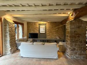 a living room with white furniture and a stone wall at Can Casellas in Palau Sator
