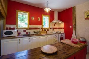 a kitchen with red walls and a wooden counter top at La maison des charretiers in Cohiniac