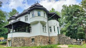 a large white house with a stone wall at Baltic Home in Polanica-Zdrój