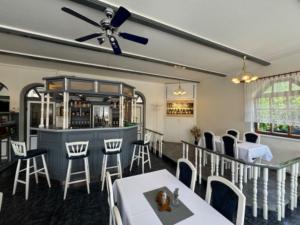a restaurant with a bar with white tables and chairs at Penzion a Rybářská bašta U Jesetera in Jeseník