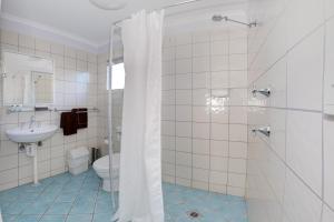 a bathroom with a shower, toilet and sink at Bali Hi Motel in Tuncurry