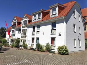 a large white building with a red roof at Am Kulturpark - Ferienwohnung mit 3 Schlafräumen für 6 Personen Neubrandenburg in Neubrandenburg