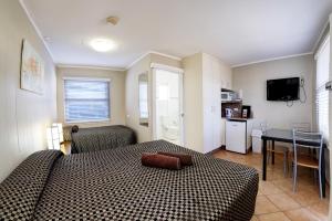 a hotel room with a bed, table, chairs and a window at Bali Hi Motel in Tuncurry