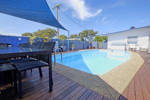 una piscina en una terraza con mesa y sillas en Bali Hi Motel en Tuncurry