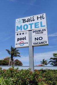 a sign on a pole with some palm trees at Bali Hi Motel in Tuncurry
