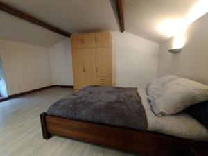 une chambre avec un lit et une armoire en bois dans l'établissement Petite maison de village, à Chamouilley