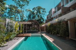 a swimming pool with a pergola next to a building at Samiik by Arkylab in Tulum