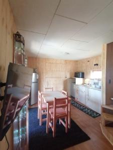 een keuken met een tafel, stoelen en een koelkast bij Chon-Vilú in Chonchi