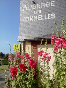 Um edifício com flores cor-de-rosa à frente. em Auberge Les Tonnelles em Saint-Léonard