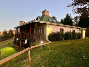 a house with a green roof on a grass field at Ndawana River Lodge in Underberg
