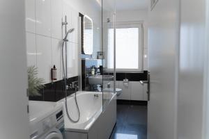 a white bathroom with a tub and a sink at JUNIK Apartments "Am Sternbuschweg" in Duisburg
