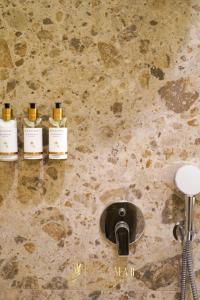 three bottles of oils on a stone wall next to a sink at OleaMar in Bar +51 photos
