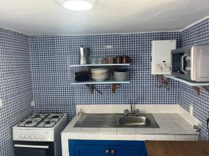 a blue tiled kitchen with a stove and a sink at Casa María in Asilah