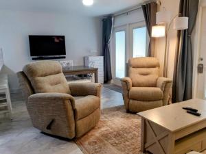 Una sala de estar con dos sillas y un televisor. en Grand Caribbean 104E, en Pensacola