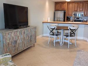 a kitchen with a table and a flat screen tv at Gulf Side Villa 1B in Pensacola