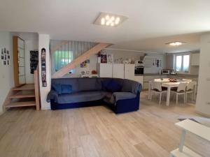 a living room with a blue couch and a kitchen at Villa Botton d'Oro Villa al lago in Lagolo di Calavino