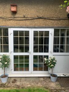 a white door with two potted plants in front of it at 1 mile from Harry Potter Tour Self Contained Flat One bedroom plus new sofa bed in lounge in Abbots Langley