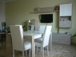 a dining room table with white chairs and a television at Guest house Il Fungo in Montefalco