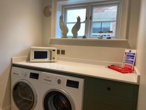 a kitchen with a washing machine and a microwave at The Bothy Cottage in Lytham St Annes