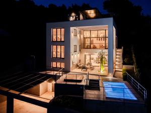 ein großes weißes Haus bei Nacht mit einem Pool in der Unterkunft Villa Blue Horizon in Nerežišće