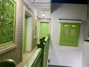 a hallway with green doors and a green railing at Dar BOUDERBALA in Mahdia