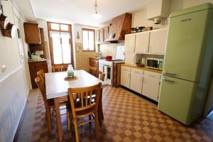 a kitchen with a table and a green refrigerator at Maison Bienvenue chez Mémé in Treigny