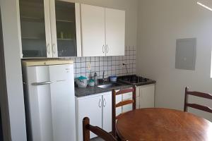 a kitchen with white cabinets and a wooden table and a tableablish at AP. 10 DO CANTINHO DO SOSSEGO in Dourados