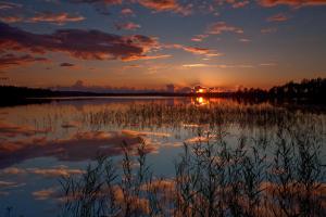 a reflection of the sunset in a lake at Atpūtas komplekss Godeļi in Usma