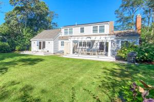 ein weißes Haus mit einem Rasen davor in der Unterkunft 2 Bicycles Provided! Cape Cod Cottage with Deck in Orleans