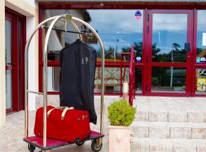 a luggage cart with a coat and a suitcase at Hotel Le Branhoc - Brit Hotel Auray in Auray