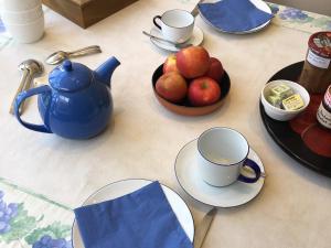 a table with a blue tea pot and a bowl of apples at B&B Woluwé - lits en mezzanine in Brussels