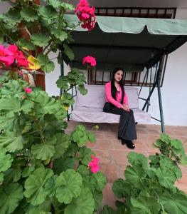 a woman sitting on a bed under a canopy with flowers at Casa Hospedaje Teresita in Chachapoyas