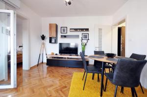 a living room with a table and chairs and a television at Apartman Chaplin in Vrnjačka Banja