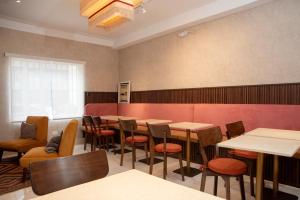 una sala da pranzo con tavoli, sedie e una parete rossa di Lima Atelier Boutique a Lima