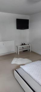 Cette chambre blanche dispose d'un lit et d'une télévision à écran plat. dans l'établissement Ferienwohnung Bad Rotenfels, à Gaggenau