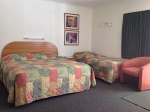 a hotel room with two beds and a chair at Breeze Motels in Greymouth