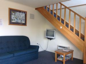 - un salon avec un canapé et une télévision dans l'établissement Breeze Motels, à Greymouth