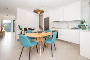 a kitchen and dining room with a wooden table and blue chairs at Vivienda Las Arecas - El Médano in El Médano