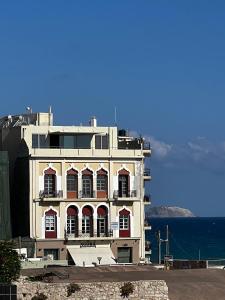 Un edificio blanco con ventanas rojas y el océano. en The Blossom Collection in Heraklion City Center, Sea View, en Heraclión