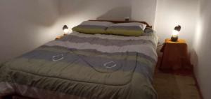 a bedroom with a bed with two lights on two tables at Wayqi Wasi in Pisac