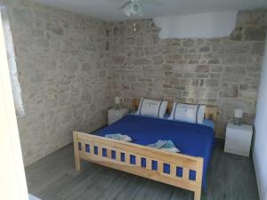 a bedroom with a blue bed and a stone wall at Yellow submarine in Olib