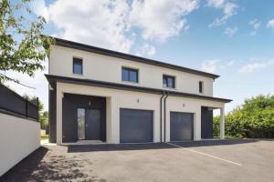 a large white house with four garage doors at La Villa Caennaise II in Grentheville