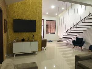 Una sala de estar con un televisor de pantalla plana en una pared. en Casa descanso Caraguá 1, en Caraguatatuba