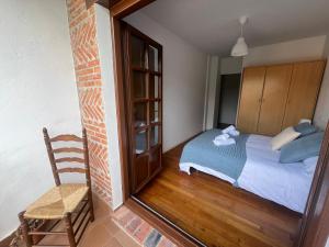 a bedroom with a bed and a chair and a mirror at Mies de Prado in Comillas