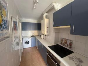 a kitchen with blue cabinets and a washer and dryer at Mies de Prado in Comillas